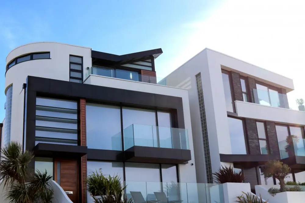 A low white clinic building with dark timber panels and glass balconies, with planting in front of it.